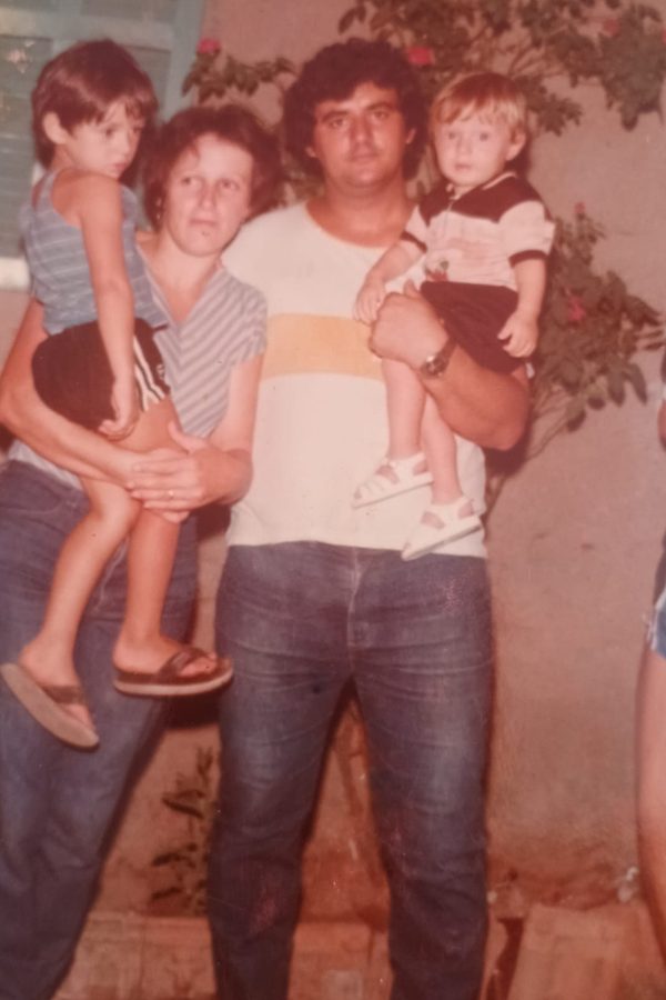 Fotografia antiga de um homem segurando uma criança, ao lado de uma mulher