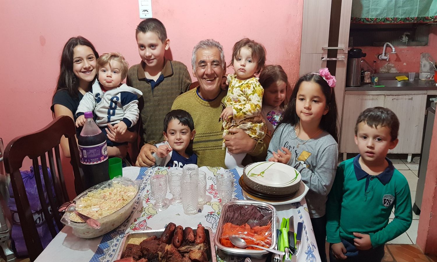 Família reunida ao redor de uma mesa, com crianças e bebês