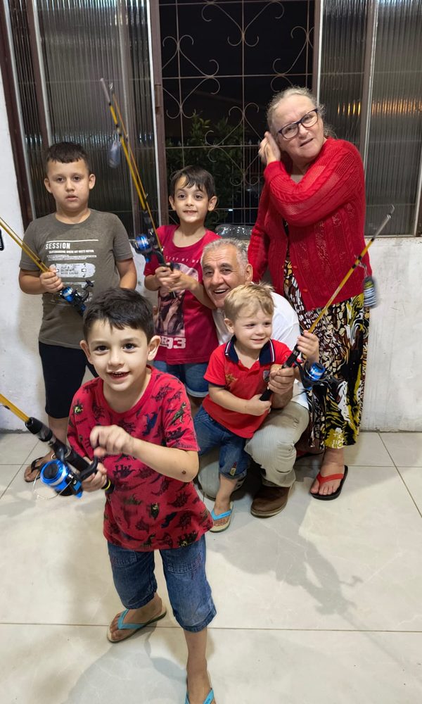 Sinval agachado com os netos, todos segurando varas de pescar