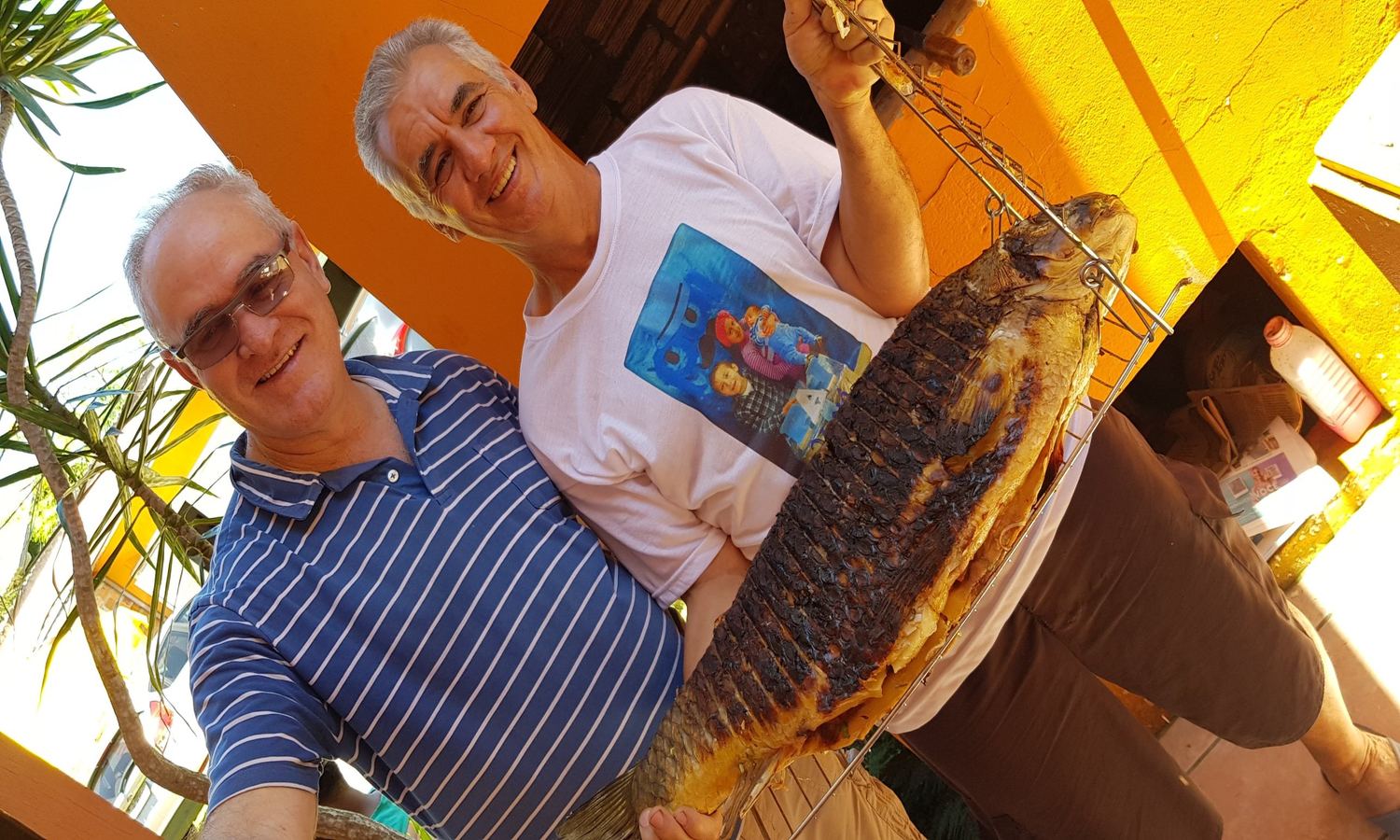 Um senhor e uma mulher segurando um peixe grande
