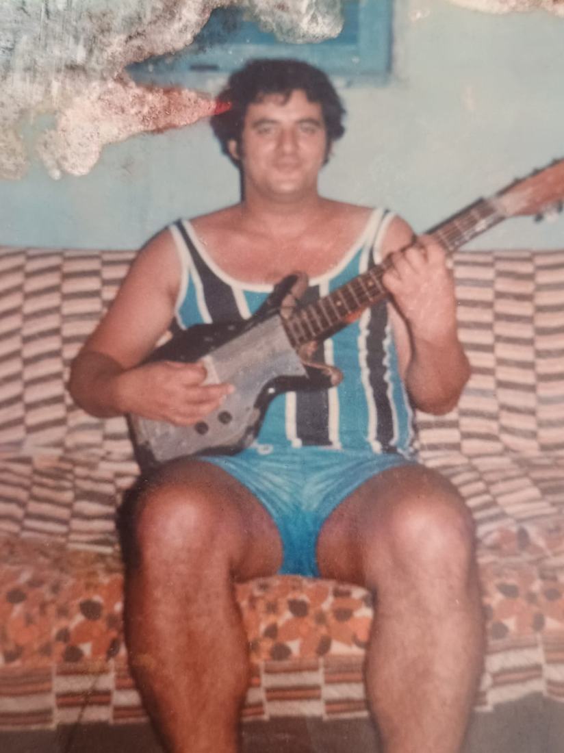 Fotografia antiga de um homem sentado tocando violão