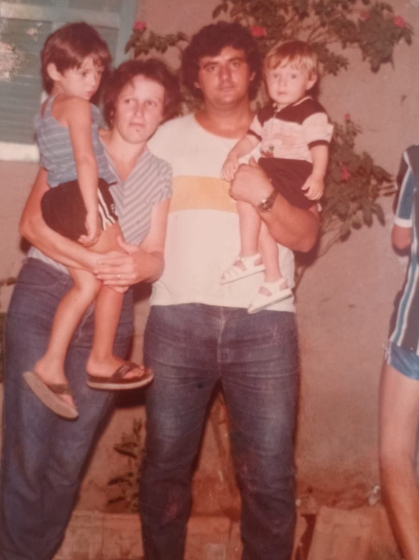 Fotografia antiga de um homem segurando uma criança, ao lado de uma mulher