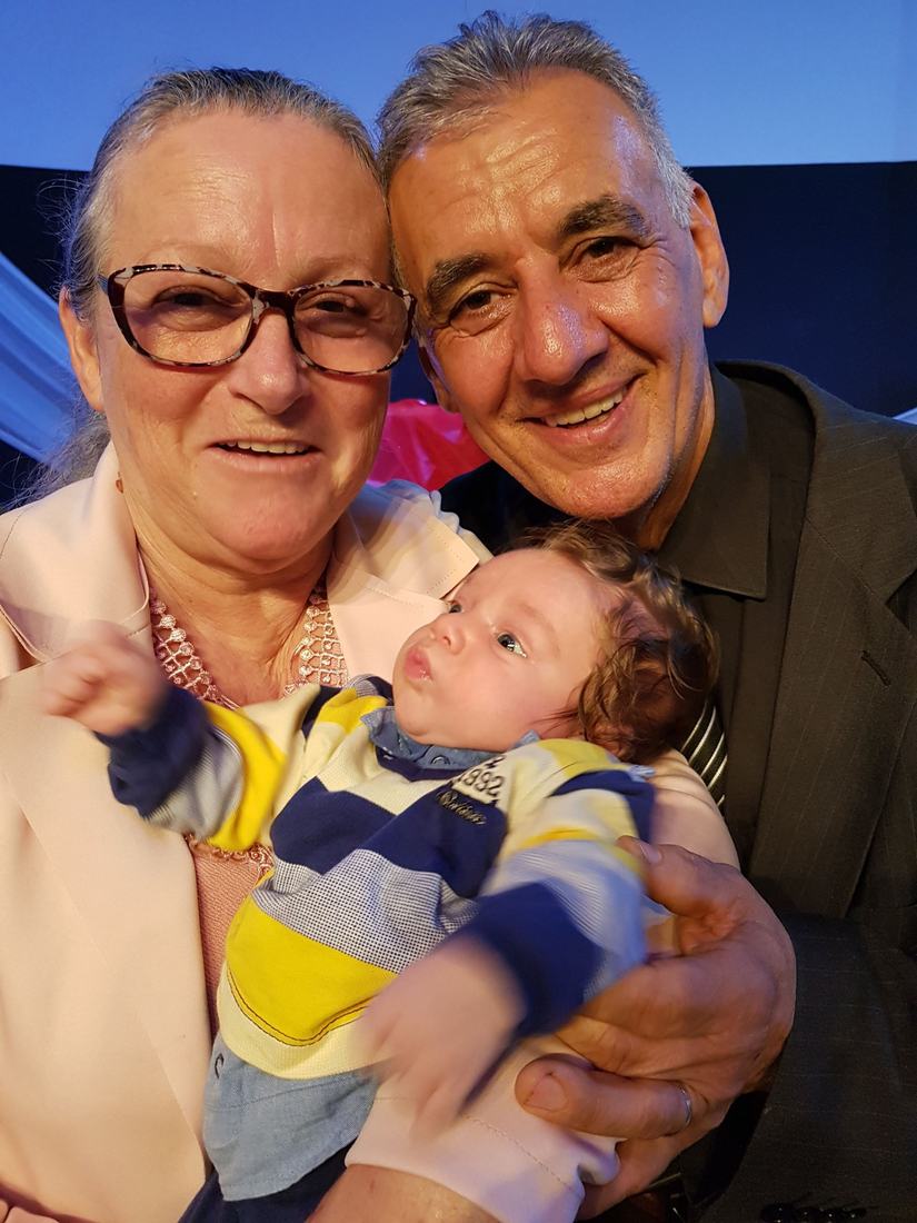 Casal sorrindo com um bebê no colo