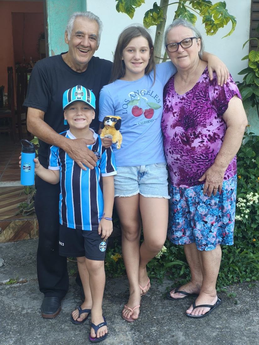 Um senhor com os netos e uma mulher, abraçados