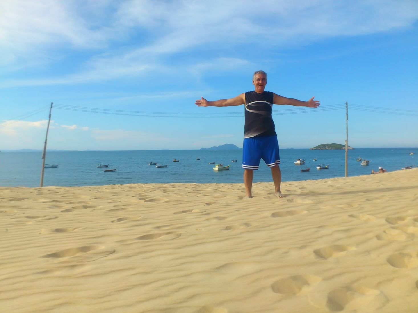Sinval de braços abertos numa praia de dunas