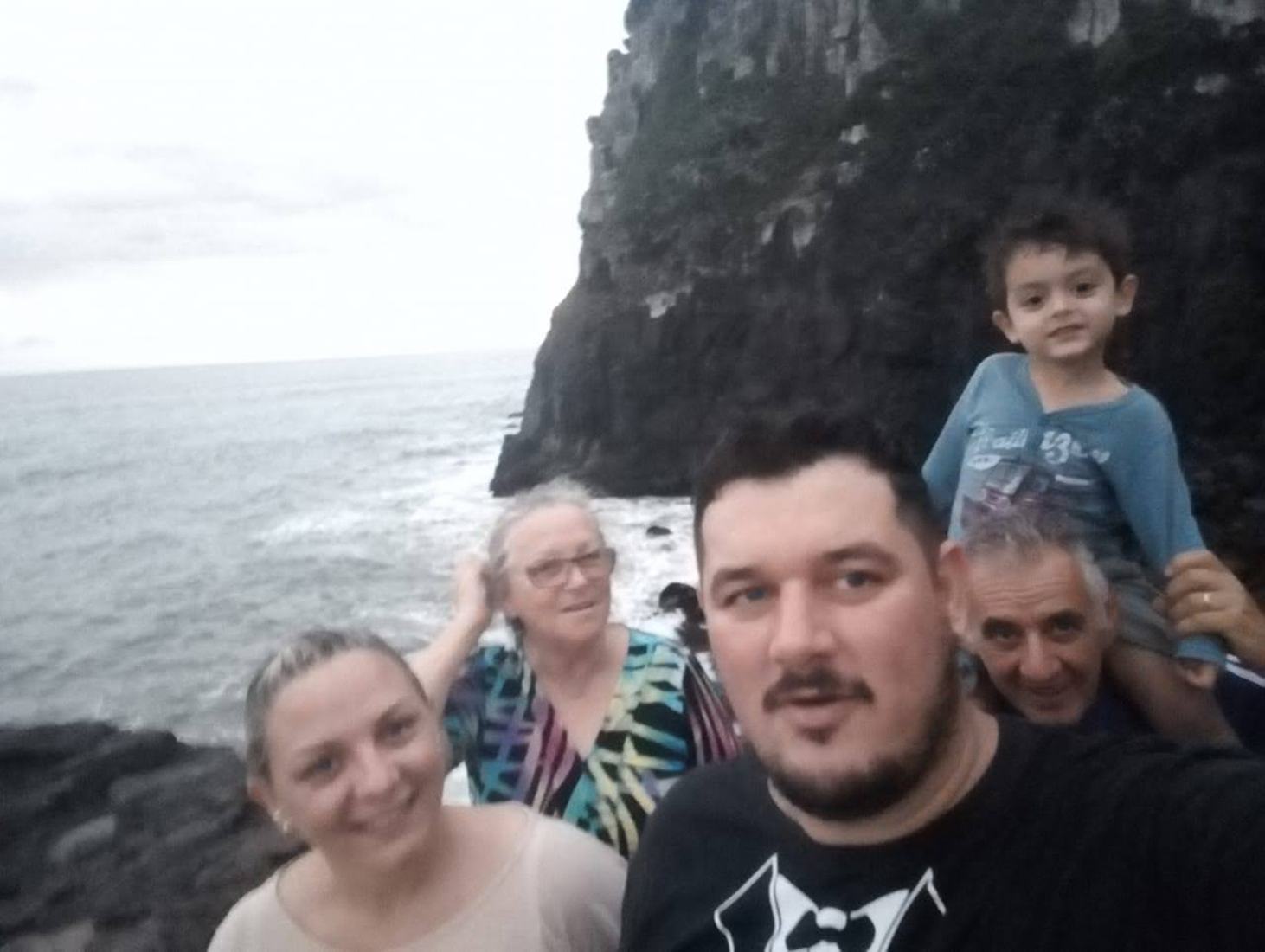 Selfie de família em frente a um penhasco à beira-mar