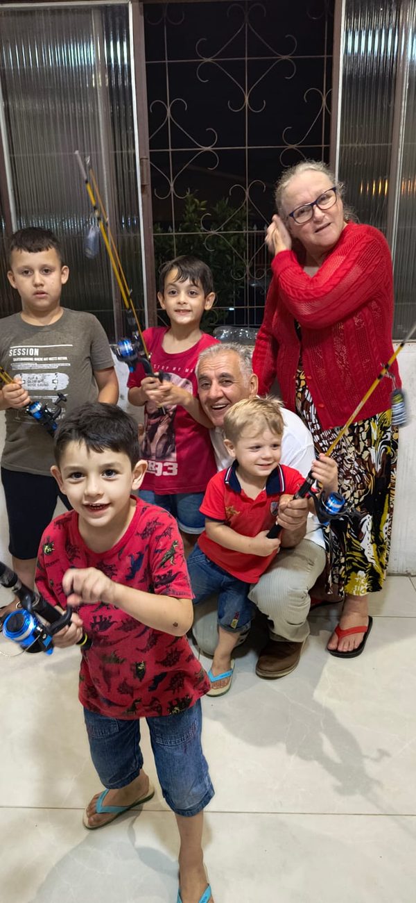 Sinval agachado com os netos, todos segurando varas de pescar