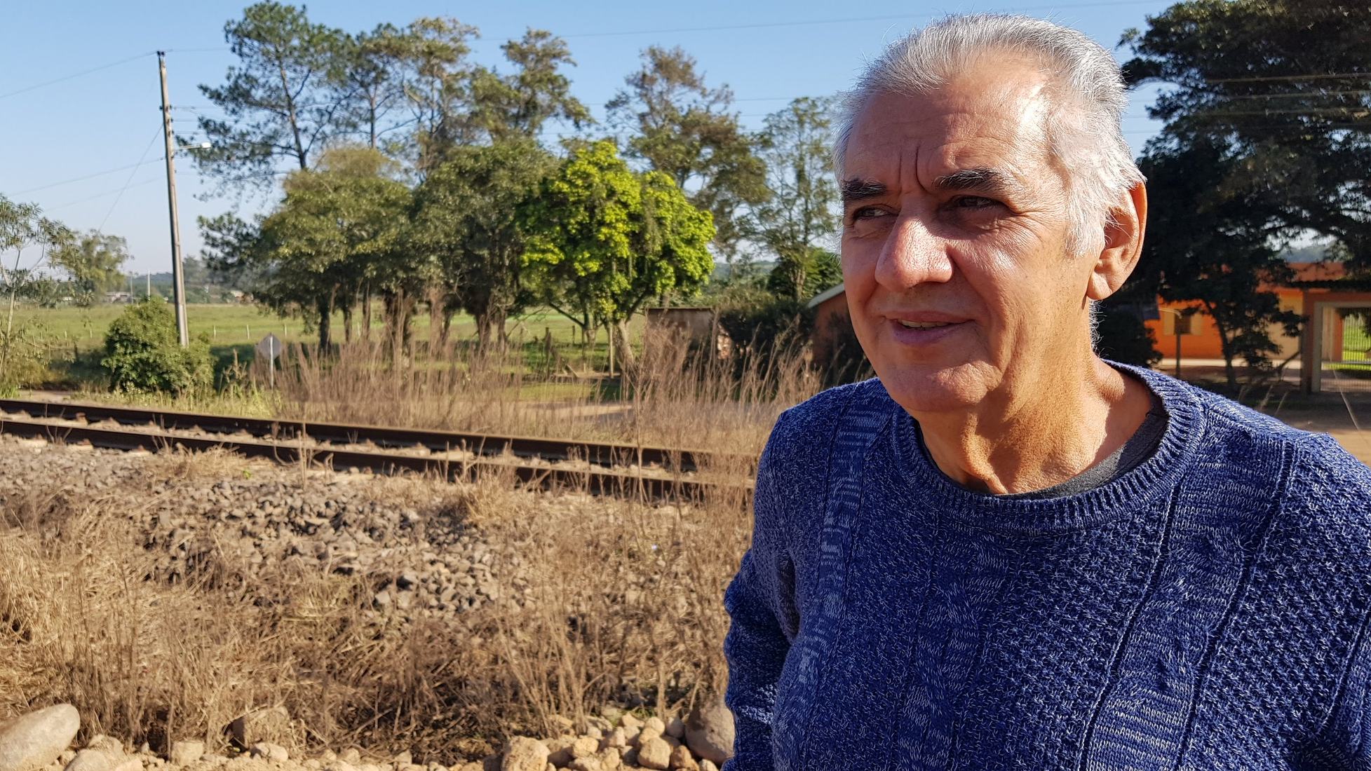 Sinval sorrindo, com a linha do trem ao fundo